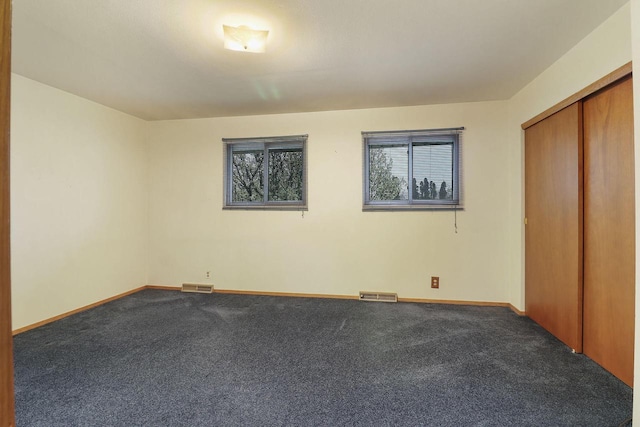 unfurnished bedroom featuring carpet floors, multiple windows, and visible vents
