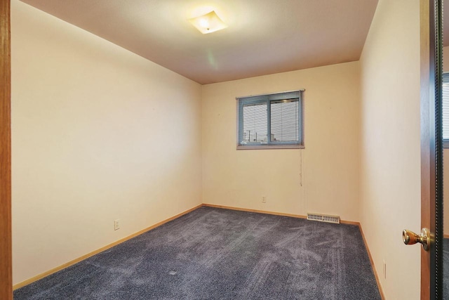 empty room with baseboards, visible vents, and dark carpet