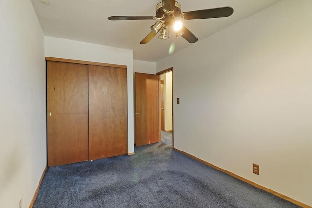 unfurnished bedroom featuring baseboards, ceiling fan, dark carpet, and a closet