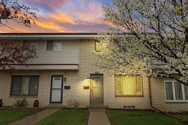 townhome / multi-family property with a lawn and brick siding