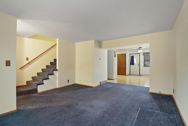 unfurnished room with ceiling fan, visible vents, baseboards, carpet, and stairs