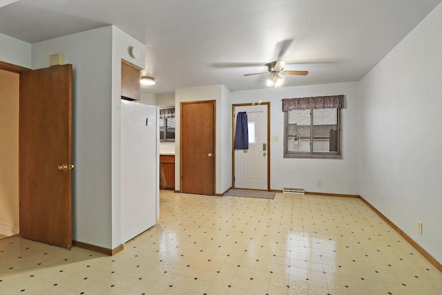 interior space featuring visible vents, a ceiling fan, light floors, and baseboards