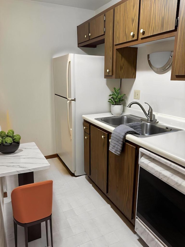 kitchen with a sink, light countertops, dishwashing machine, and light floors