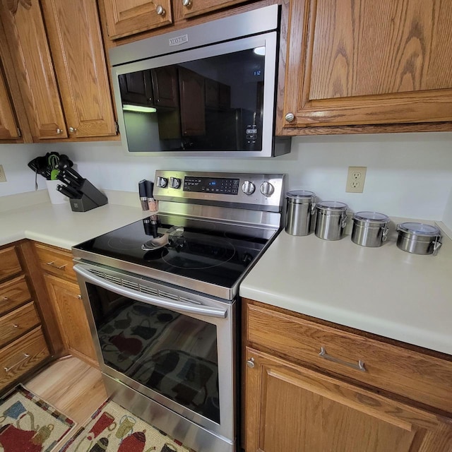 kitchen with light countertops, stainless steel appliances, and brown cabinetry