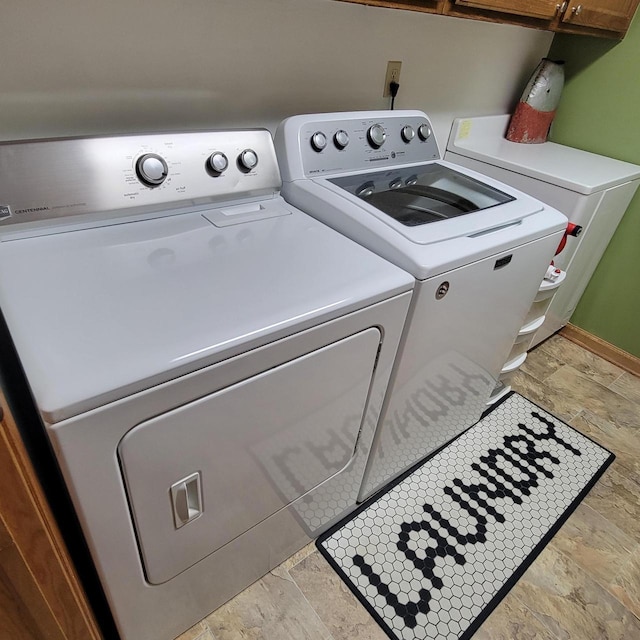 washroom featuring separate washer and dryer, stone tile floors, and cabinet space