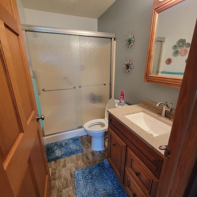 full bath with vanity, a shower stall, toilet, and wood finished floors