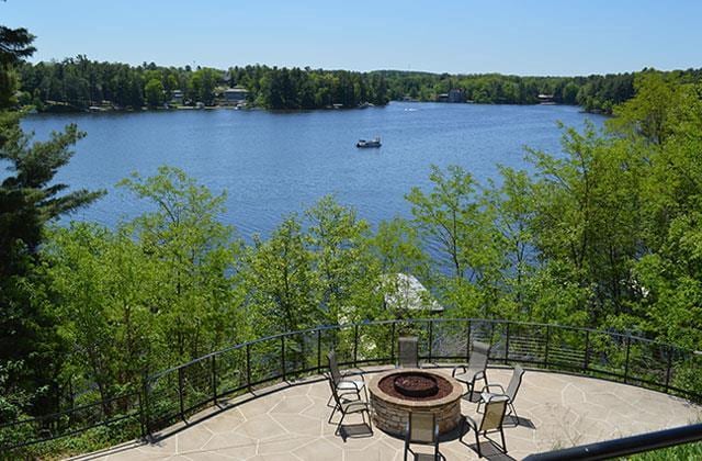 view of patio with a water view, a view of trees, and an outdoor fire pit