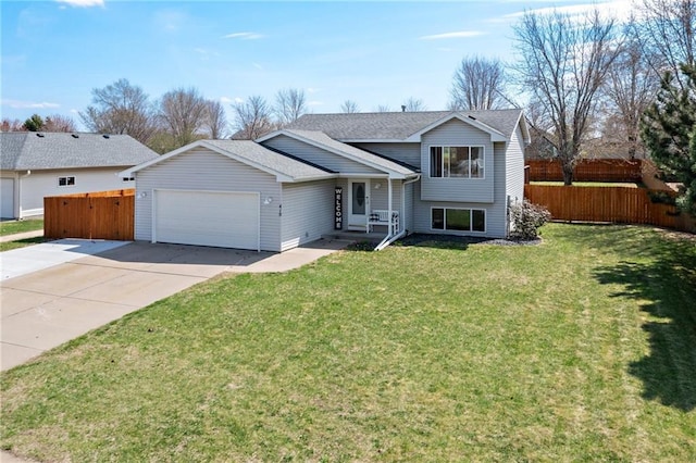 split level home with a garage, a front lawn, fence, and driveway