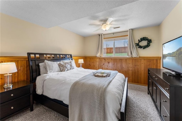 bedroom with visible vents, wood walls, wainscoting, and light carpet