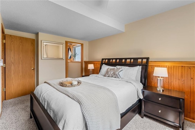 bedroom featuring carpet floors, wooden walls, a closet, and a wainscoted wall