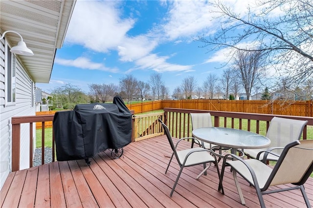 wooden terrace featuring a yard, outdoor dining area, and a fenced backyard