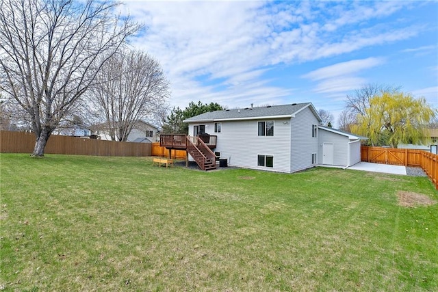 back of house featuring stairway, a yard, a wooden deck, and a fenced backyard