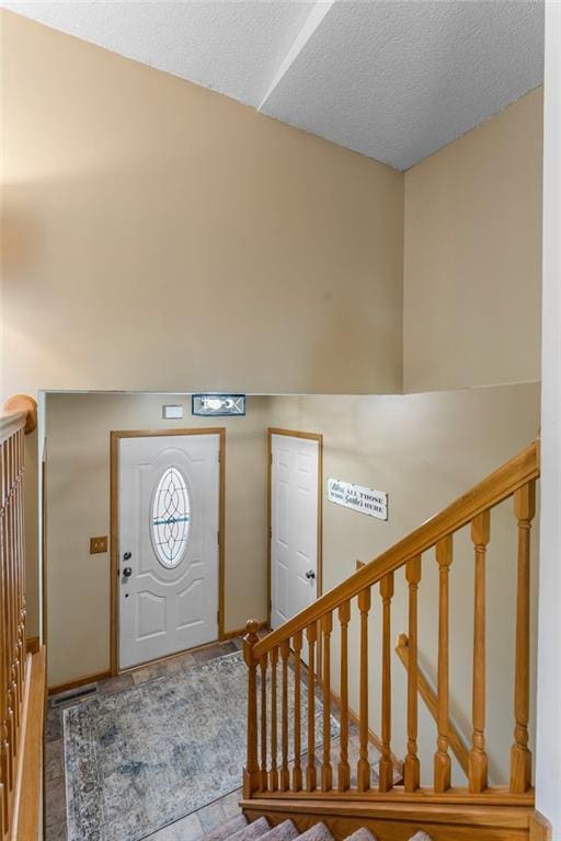 foyer featuring baseboards, a textured ceiling, stairs, and wood finished floors