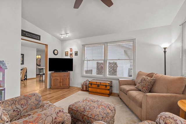 living area with baseboards, ceiling fan, vaulted ceiling, and light wood-style flooring