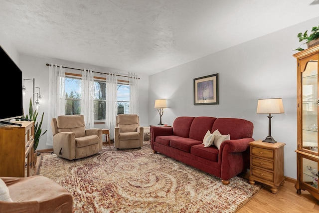 living room featuring light wood-style floors, baseboards, and a textured ceiling