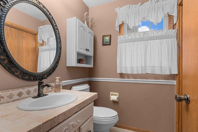 half bathroom with vanity, tile patterned floors, and toilet