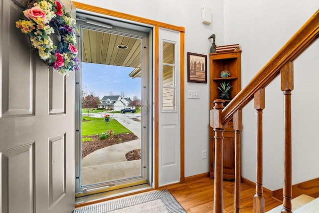 foyer entrance featuring stairs, baseboards, and light wood finished floors