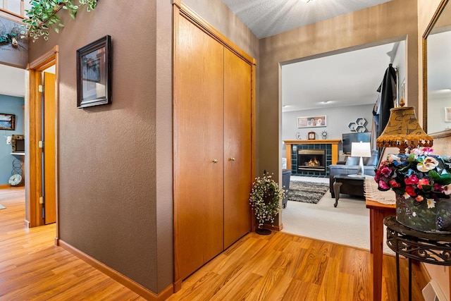 hall featuring light wood-style flooring and a textured wall