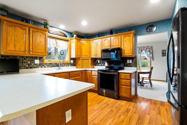 kitchen with brown cabinets, a sink, light countertops, black appliances, and recessed lighting