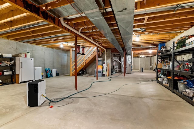 unfinished basement with freestanding refrigerator and heating unit