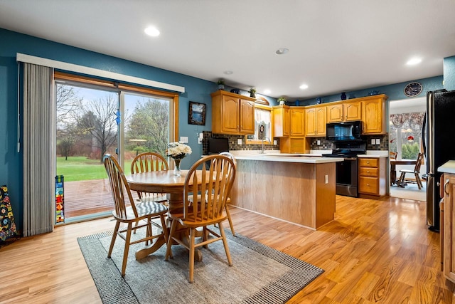 kitchen featuring a peninsula, appliances with stainless steel finishes, light wood-type flooring, and light countertops