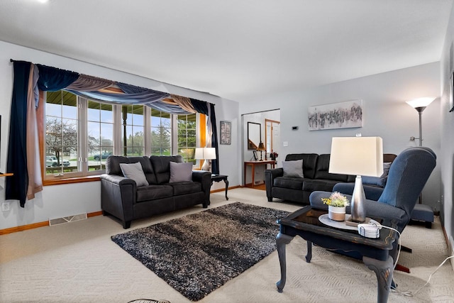 living area with baseboards, visible vents, and carpet