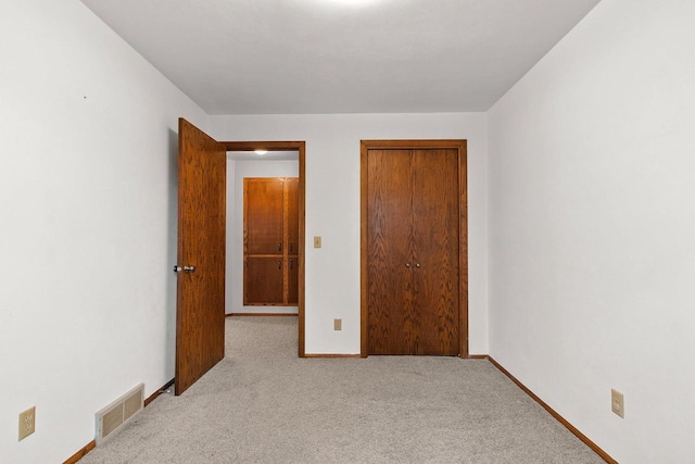 unfurnished bedroom featuring carpet floors, baseboards, a closet, and visible vents