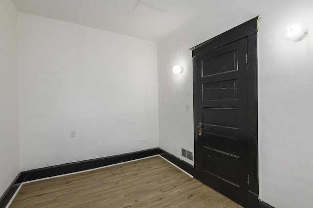 spare room featuring visible vents, baseboards, and wood finished floors