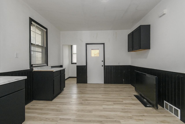 kitchen featuring dark cabinets, light countertops, light wood finished floors, and visible vents