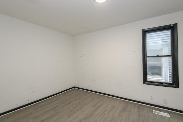 spare room featuring baseboards, wood finished floors, and visible vents