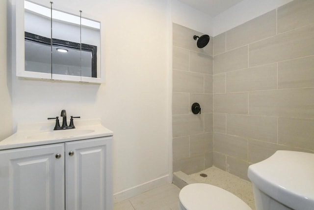 bathroom with a tile shower, vanity, tile patterned floors, baseboards, and toilet