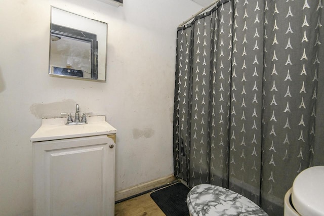 bathroom featuring toilet, baseboards, a shower with shower curtain, and vanity