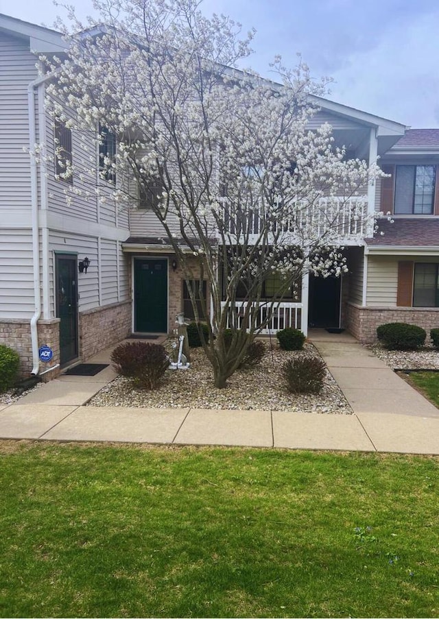 multi unit property with brick siding and a front lawn