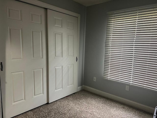unfurnished bedroom featuring baseboards, light carpet, and a closet
