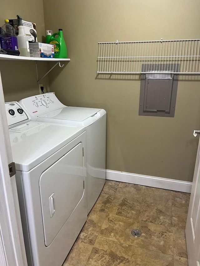 washroom with laundry area, stone finish flooring, washing machine and dryer, and baseboards