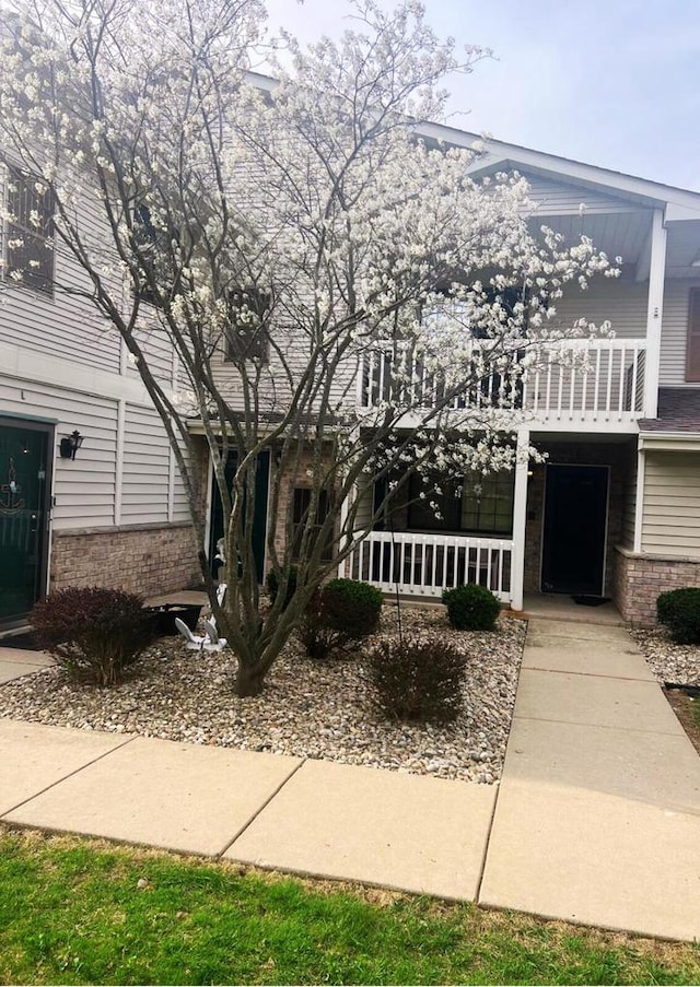 view of front of home with covered porch, brick siding, and a balcony