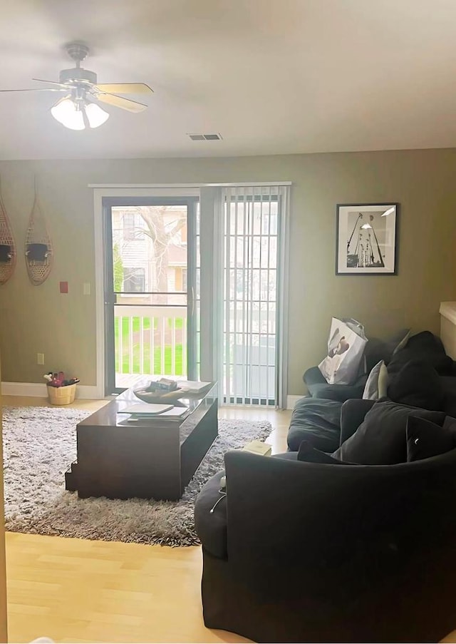 living area featuring baseboards, ceiling fan, visible vents, and wood finished floors