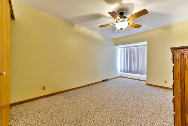 unfurnished room featuring baseboards, visible vents, ceiling fan, and carpet