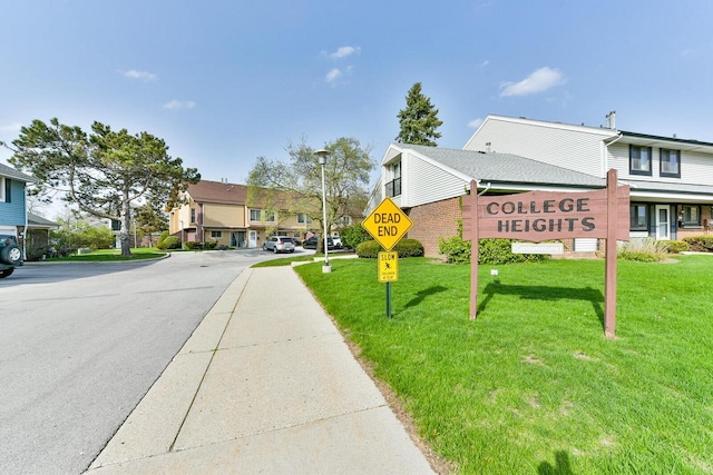 community / neighborhood sign featuring a residential view and a lawn
