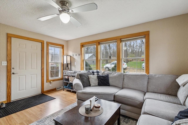 living area with baseboards, a ceiling fan, wood finished floors, and a healthy amount of sunlight
