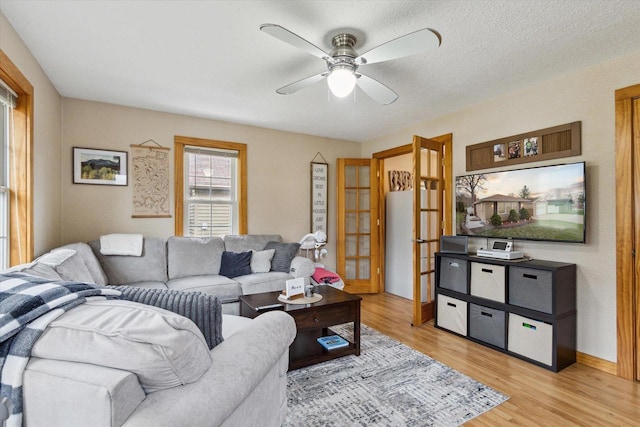 living room featuring french doors, a ceiling fan, and light wood finished floors