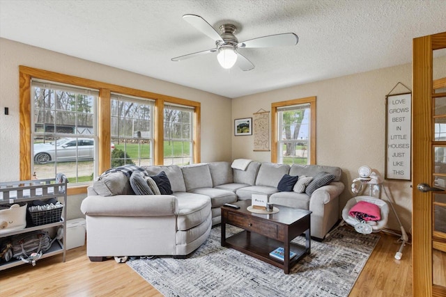 living room featuring a textured ceiling, a ceiling fan, wood finished floors, and a wealth of natural light
