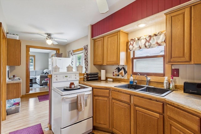 kitchen with a sink, light countertops, a ceiling fan, and electric range