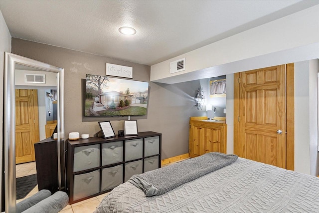 tiled bedroom with a textured ceiling and visible vents