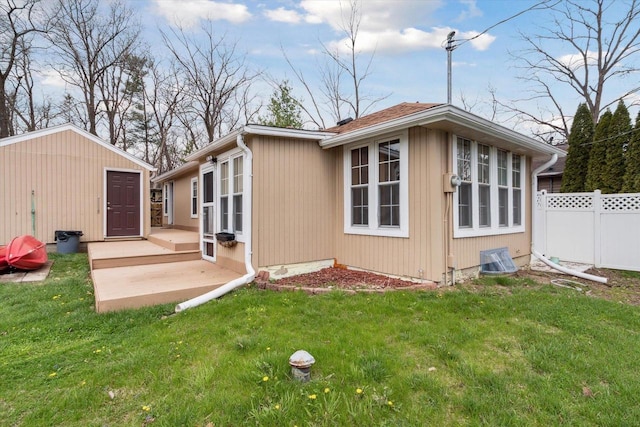 view of home's exterior featuring a lawn, fence, an outdoor structure, and a patio area