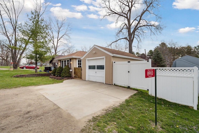 view of home's exterior with concrete driveway, a yard, fence, and a gate
