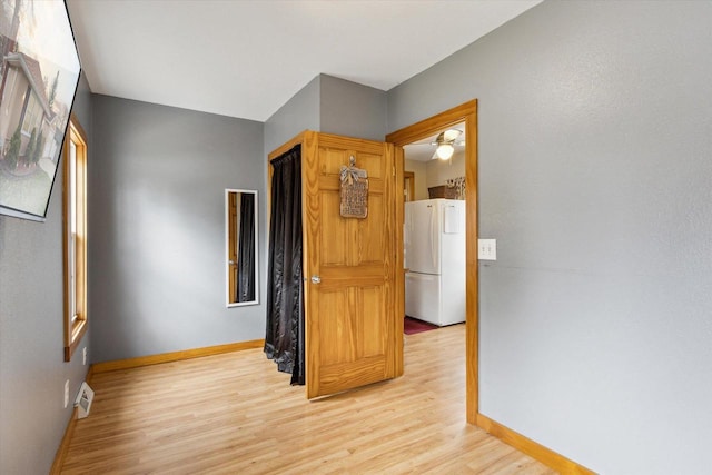 corridor featuring baseboards, light wood-type flooring, and visible vents