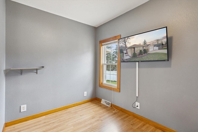 spare room featuring baseboards, wood finished floors, and visible vents