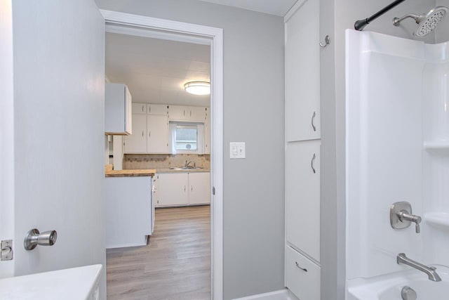 bathroom with vanity, washtub / shower combination, wood finished floors, and tasteful backsplash