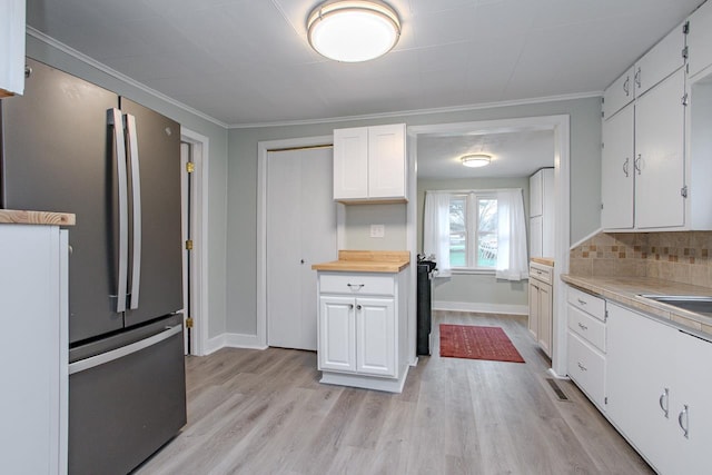 kitchen with freestanding refrigerator, baseboards, light wood-type flooring, light countertops, and white cabinets